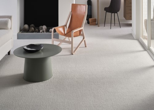 light colored carpet in living room with orange chair and round coffee table