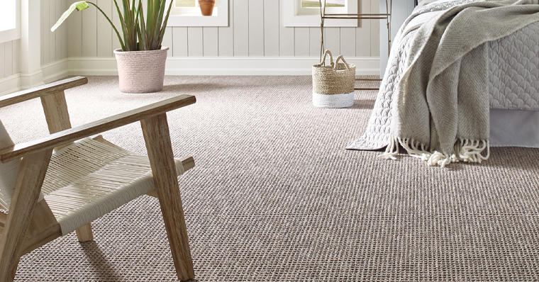 textured carpet in a bedroom with bed, blanket, chair, and plant